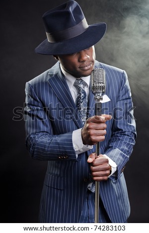 Black man with blue striped suit and blue hat singing. Smoky nightclub like a cotton club