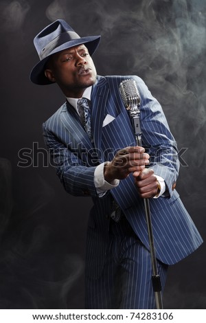 Black man with blue striped suit and blue hat singing. Smoky nightclub like a cotton club