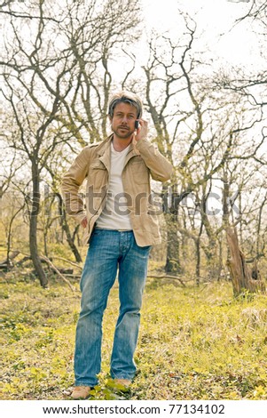 Young casual man calling with his mobile phone walking in nature.