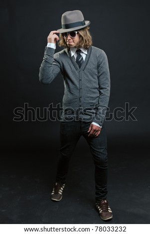 Studio portrait of hip cool looking young man with hat and white sunglasses on black background.