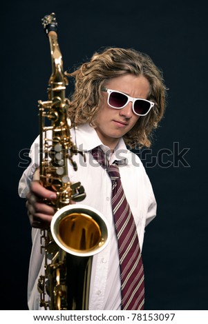 Studio portrait of young hip cool man long blond hair white sunglasses with saxophone on black background.
