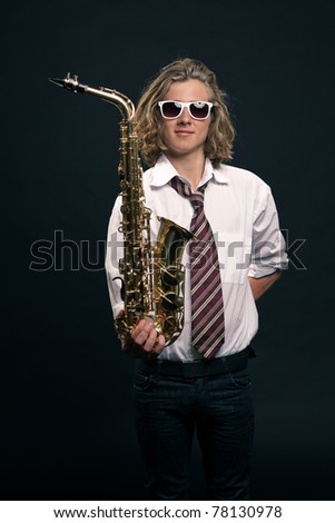 Studio portrait of young hip cool man with saxophone and white sunglasses on black background.