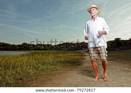 Senior man with hat and short and white shirt enjoying nature on hot summer day.