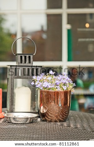 Flowers and candle on table of terrace of cafe.