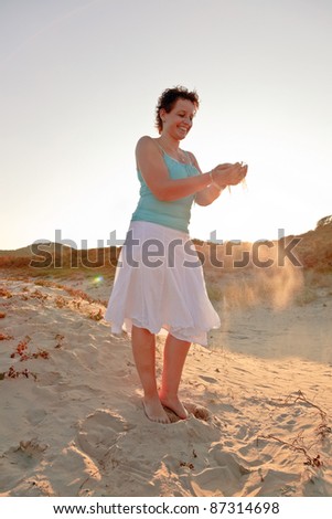 Casual young woman playing with sand enjoying outdoor dune landscape on sunny day