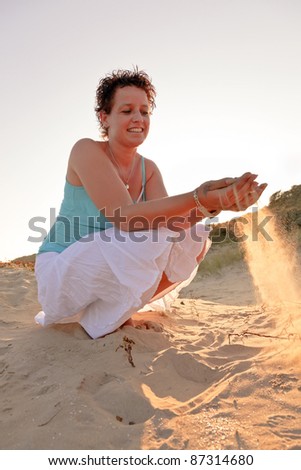 Casual young woman playing with sand enjoying outdoor dune landscape on sunny day