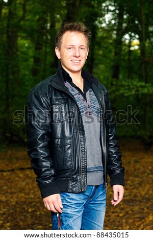 Single casual young man in forest. Short hair wearing jeans and black leather jacket.