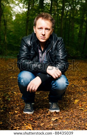 Single casual young man in forest. Short hair wearing jeans and black leather jacket.
