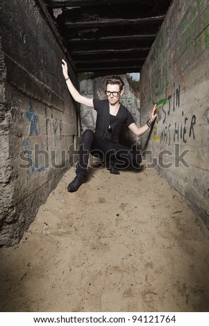 Urban style handsome young man with fifties hairstyle dressed in black wearing glasses