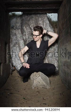 Urban style handsome young man with fifties hairstyle dressed in black wearing glasses