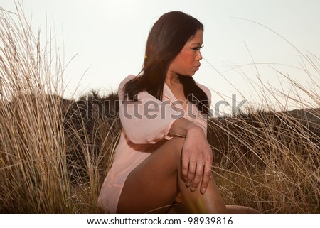 Pretty young black woman posing in dune landscape with clear blue sky. Enjoying outdoors.