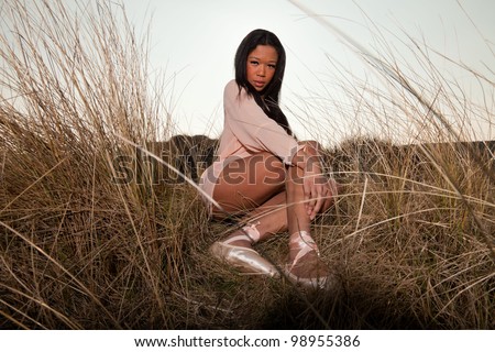 Pretty young black woman posing in dune landscape with clear blue sky. Enjoying outdoors. Wearing ballerina shoes.