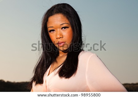 Pretty young black woman posing in dune landscape with clear blue sky. Enjoying outdoors. Looking sensual.