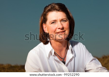 Attractive woman middle aged enjoying outdoors. Clear sunny spring day with blue sky.