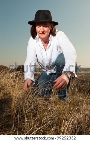 Attractive confident woman wearing a hat middle aged enjoying outdoors. Clear sunny spring day with blue sky.