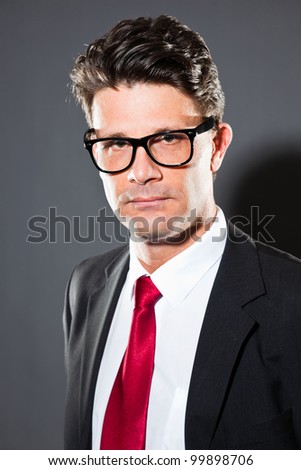 Business man with grey suit and red tie isolated on dark background. Wearing retro glasses. Studio shot.