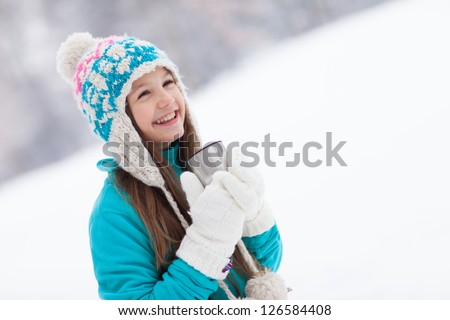 Young girl drinking from thermos cup in winter