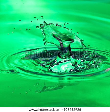 Two water drops meeting in mid-air on a green surface