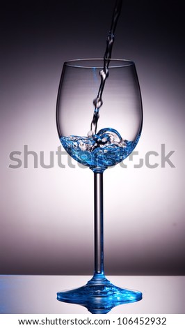 Small amount of transparent liquid in wine glass with back-lighting