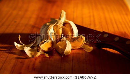 Low light image of garlic and knife on a wooden surface