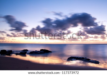 Sunrise over the sea with the sun\'s reflection in the wet sand