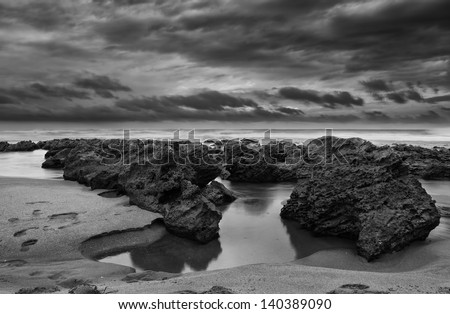 Sunrise landscape of ocean with waves clouds and rocks black and white (Artistic processing) high contrast