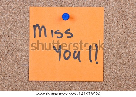 Post it note orange with miss you message on cork