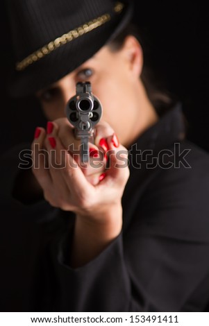 Dangerous woman in black with silver handgun and stylish hat