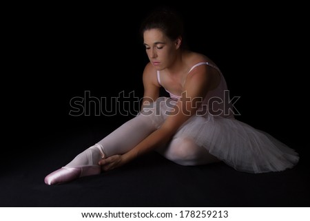 Female dancer sit on floor looking sad in pink tutu and slippers low key