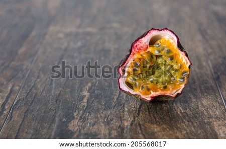 Ripe old passion fruit sliced in halve close-up on brown surface