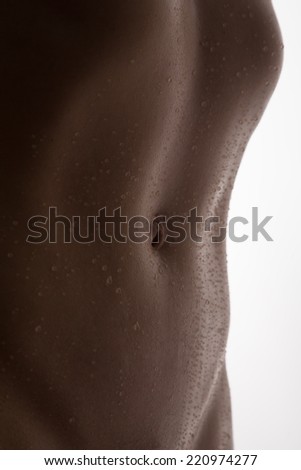 Bodyscape of a nude woman with wet stomach and back lighting in artistic conversion