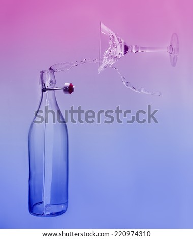 Clear water pour horizontal out of bottle splash into glass with a blue and pink back lighting