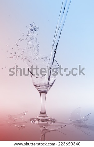 Clear water spill from a broken wine glass on a colour background
