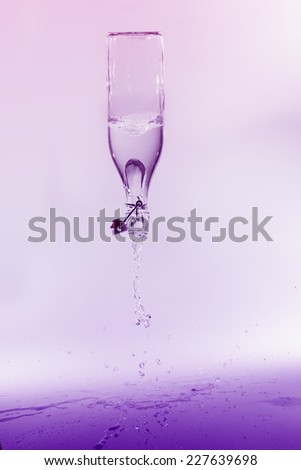 Clear water spill from a glass bottle on a purple background on shiny surface