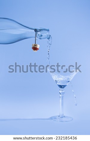 Clear water pour out of bottle splash into glass and spill with a blue back lighting