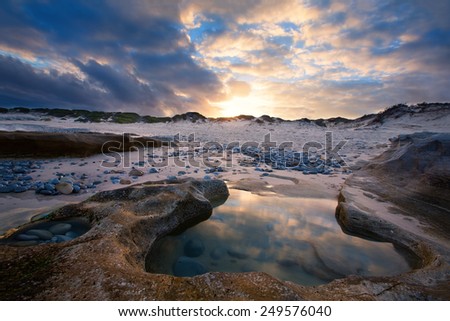 Late evening landscape beach over rocky shore with glowing sunset