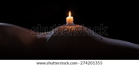 Body scape of a well-shaped woman with a burning candle and wax on her bum