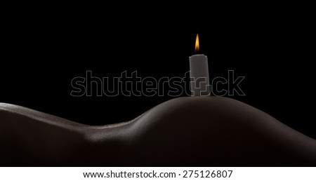 Body scape of a well-shaped woman with a burning candle on her bum
