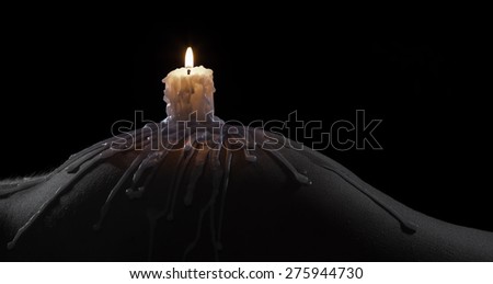 Body scape of a well-shaped woman with a burning candle and wax on her bum