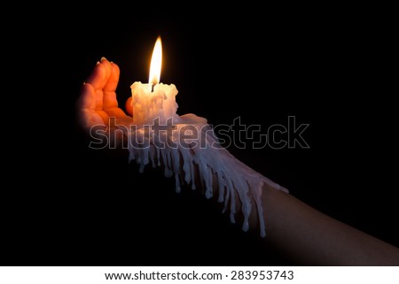 Open hand holding a candle stick with wax flowing down the arm