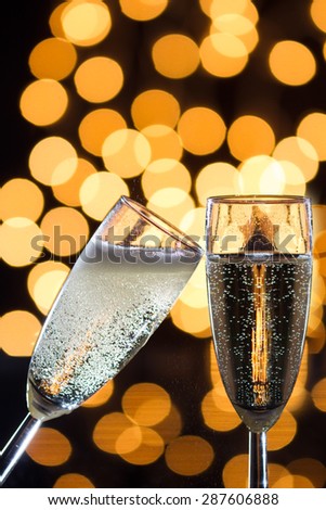 Two champagne glasses with bubbles and bokeh lights in the background
