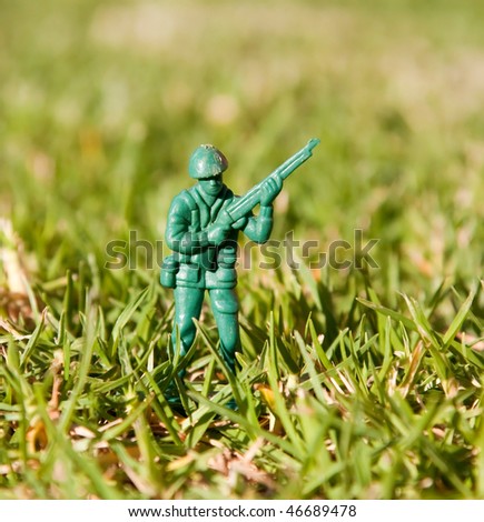 Plastic toy soldier with rifle standing in green grass