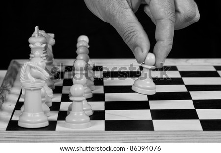 White chess pieces with hand playing on wooden board