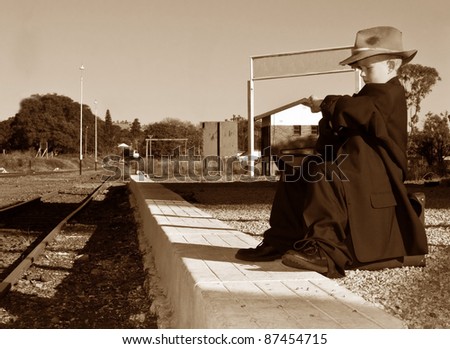 Boy with big clothes waiting for a train on a station