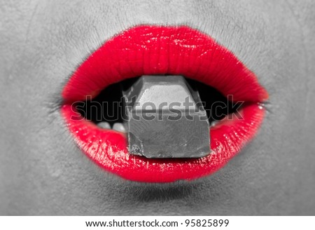 Black and white photo with red, hot lips biting a chocolate