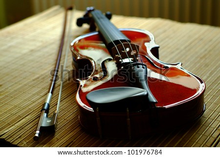 violin with a bow lying on a mat from a bamboo