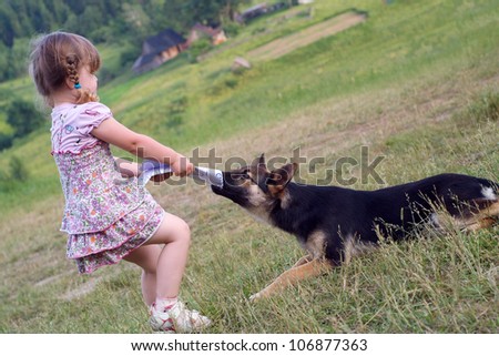 the girl plays with a sheep-dog and takes away sheets of paper from a dog