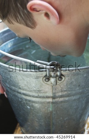 The boy drinking water from a bucket
