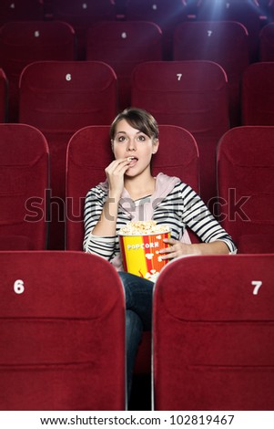 Excited woman with popcorn in the movie theater