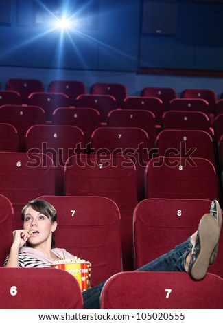 A girl with popcorn sitting alone at the cinema